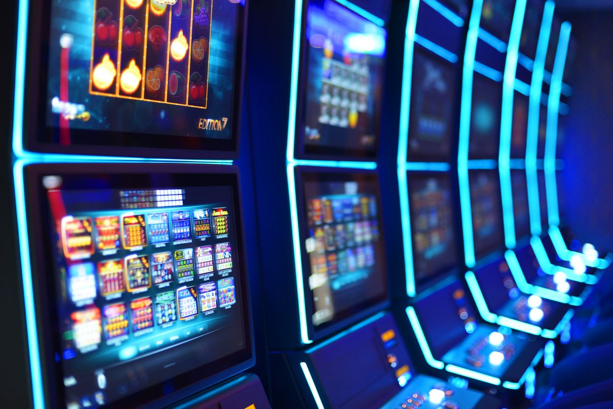 Moderne Spielautomaten mit bunten Bildschirmen in einem dunklen Raum.
