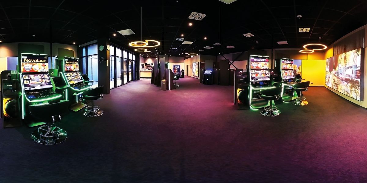 Innenraum einer Admiral Spielhalle mit vielen bunten Automaten und dunkelrotem Boden.